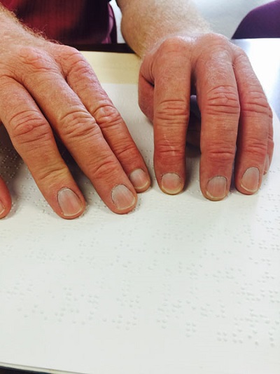 reading Braille dots with fingers on the page