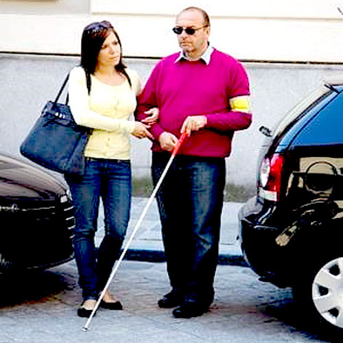 a woman is guiding a blind man to her car for a doctors appointment